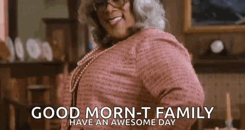 A Woman In A Pink Sweater And Glasses Is Smiling And Says `` Good Morning - T Family Have An Awesome Day '' . GIF