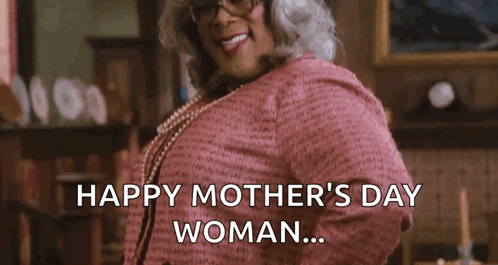 A Woman In A Pink Sweater And Pearls Is Standing In A Living Room . GIF