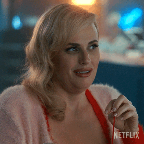 A Woman In A Pink Sweater Is Holding A Red Ribbon With Netflix Written On The Bottom Right GIF