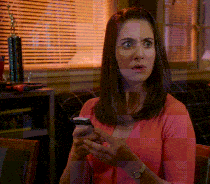a woman in a pink sweater is looking at her cell phone