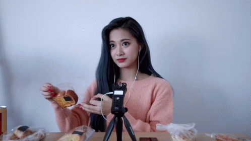 a woman in a pink sweater is sitting at a table eating food