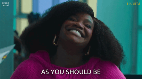 A Woman In A Pink Sweater Is Smiling And Says As You Should Be GIF