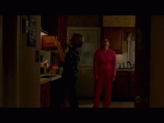 A Woman In A Pink Sweater Is Standing In A Kitchen GIF