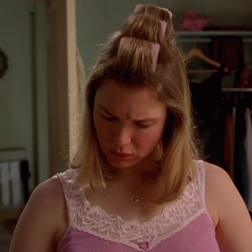 A Woman In A Pink Tank Top And White Lace Trim Looks Down GIF