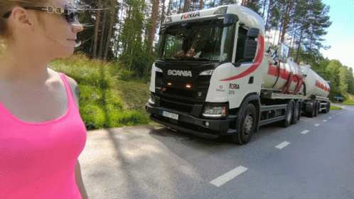 A Woman In A Pink Tank Top Is Standing In Front Of A Scania Truck GIF