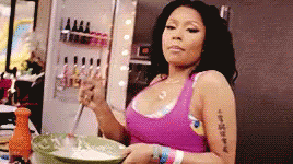 A Woman In A Pink Tank Top Is Stirring Something In A Bowl . GIF