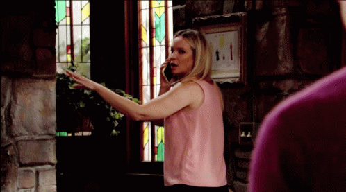 A Woman In A Pink Tank Top Is Talking On A Cell Phone GIF