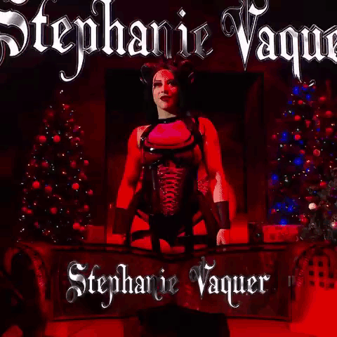 A Woman In A Pink Top And Black Corset Is Standing In Front Of A Red Background With The Name Stephanie Vaquer On It . GIF