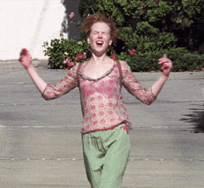 A Woman In A Pink Top And Green Pants Is Screaming With Her Arms In The Air GIF