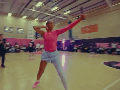 A Woman In A Pink Top And White Shorts Is Holding A Sword GIF
