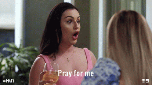 A Woman In A Pink Top Is Holding A Wine Glass And Says Pray For Me GIF