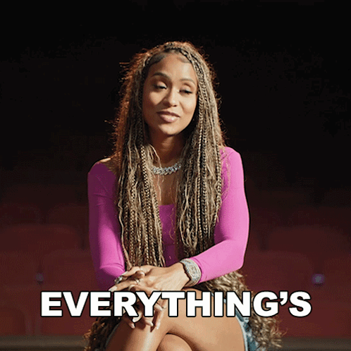 a woman in a pink top is sitting with her legs crossed and the words everything 's behind her