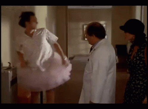 A Woman In A Pink Tutu Is Standing Next To A Doctor And A Woman In A Black Dress . GIF