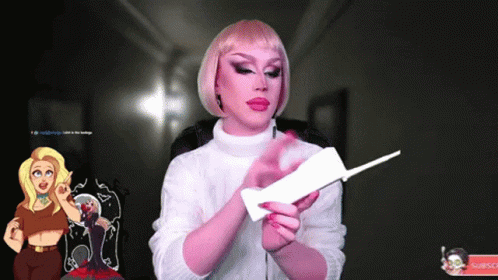 A Woman In A Pink Wig Is Holding A Piece Of Paper GIF