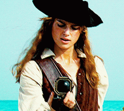 A Woman In A Pirate Costume Is Holding A Cannon GIF