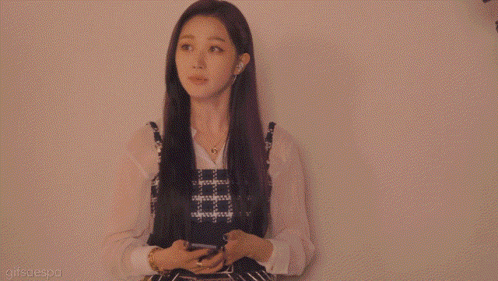 a woman in a plaid dress is standing in front of a white wall