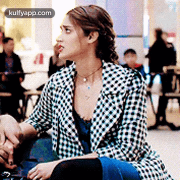 A Woman In A Plaid Jacket Is Sitting At A Table In A Cafe . GIF