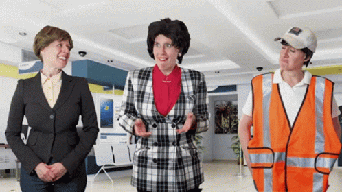 A Woman In A Plaid Jacket Stands Next To Two Other Women GIF