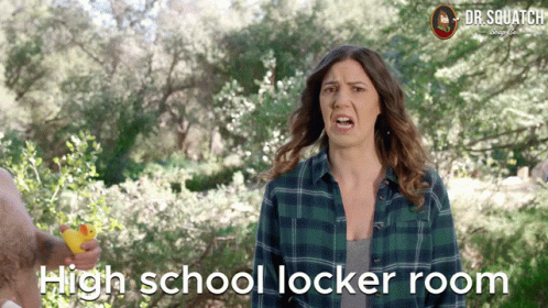 A Woman In A Plaid Shirt Is Holding A Yellow Rubber Duck In Front Of Trees And The Words High School Locker Room GIF