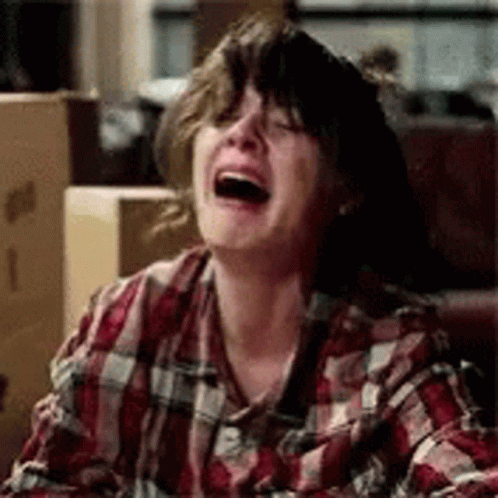 A Woman In A Plaid Shirt Is Laughing And Crying . GIF