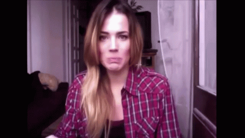 A Woman In A Plaid Shirt Is Making A Face . GIF