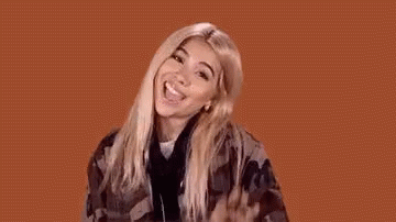 A Woman In A Plaid Shirt Is Making A Funny Face And Waving Her Hand In The Air . GIF