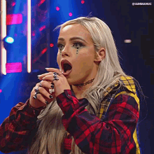 A Woman In A Plaid Shirt Is Making A Funny Face With Her Mouth Open . GIF