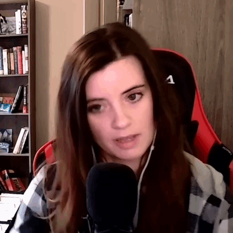 A Woman In A Plaid Shirt Is Sitting In A Red Chair With A Microphone . GIF