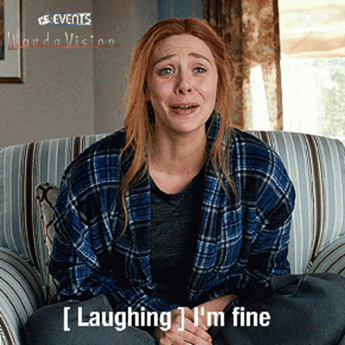 A Woman In A Plaid Shirt Is Sitting On A Couch With The Words Laughing I 'M Fine Below Her GIF