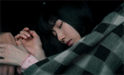 A Woman In A Plaid Shirt Is Sleeping Under A Blanket GIF