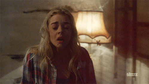 A Woman In A Plaid Shirt Is Standing In Front Of A Lamp With The Word Starz On The Bottom GIF