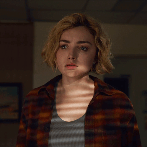 A Woman In A Plaid Shirt Looks At The Camera With A Serious Look On Her Face GIF