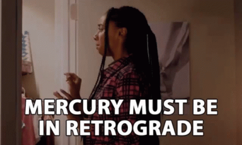 A Woman In A Plaid Shirt Stands In Front Of A Door With The Words " Mercury Must Be In Retrograde " GIF