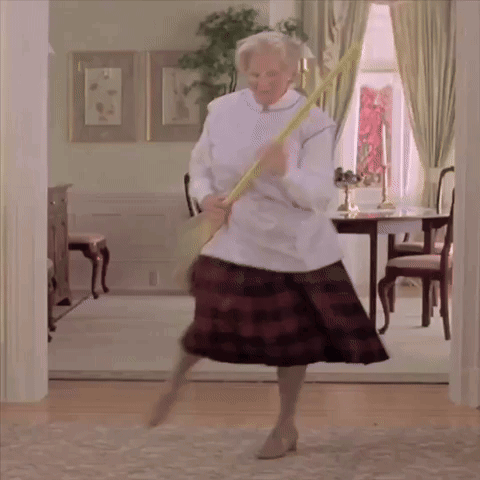 A Woman In A Plaid Skirt Is Holding A Broom In Her Hand GIF