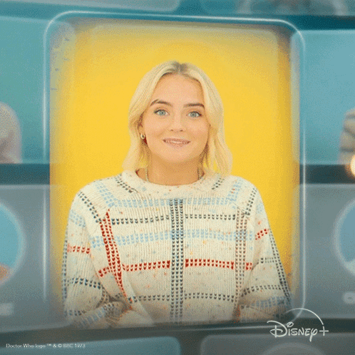 A Woman In A Plaid Sweater Is Smiling In Front Of A Yellow Background That Says Disney GIF