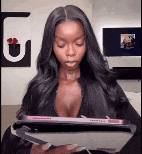 A Woman In A Plunging Top Is Holding A Tablet GIF