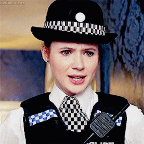 A Woman In A Police Uniform Has A Walkie Talkie On Her Vest GIF