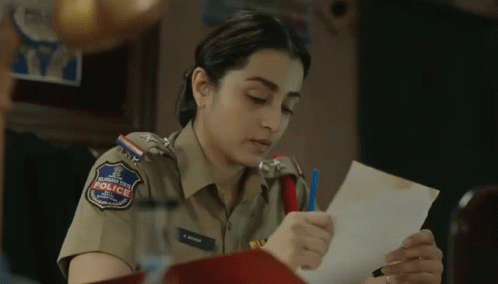 A Woman In A Police Uniform Is Holding A Piece Of Paper In Her Hand . GIF