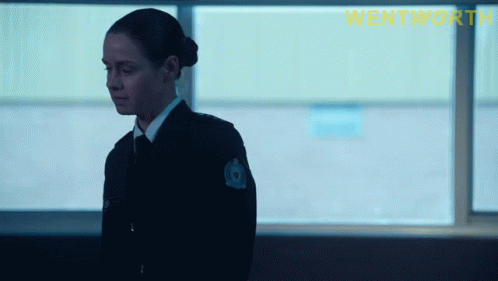 A Woman In A Police Uniform Is Standing In Front Of A Window With The Word Wentworth On The Bottom Right GIF