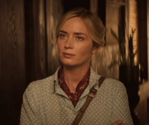 A Woman In A Polka Dot Shirt And Scarf Is Standing In A Hallway GIF