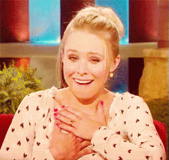 A Woman In A Polka Dot Shirt Is Smiling With Her Hand On Her Chest GIF