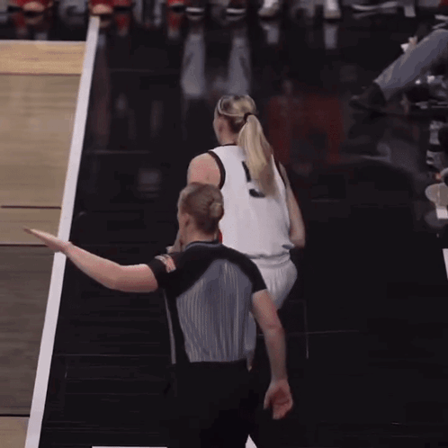 A Woman In A Ponytail Stands Next To A Referee GIF