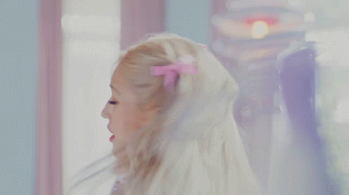 A Woman In A Purple Dress Is Looking At Her Reflection In A Mirror GIF