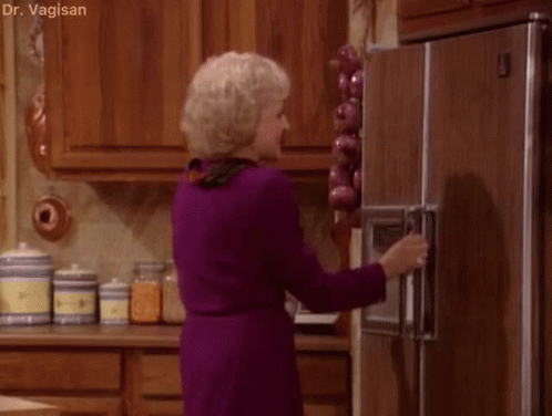 A Woman In A Purple Dress Is Opening The Door Of A Refrigerator . GIF