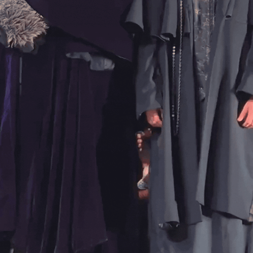 a woman in a purple dress is peeking out from behind a purple cloth