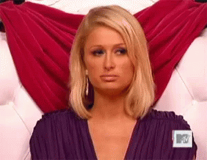 A Woman In A Purple Dress Is Sitting On A Couch . GIF