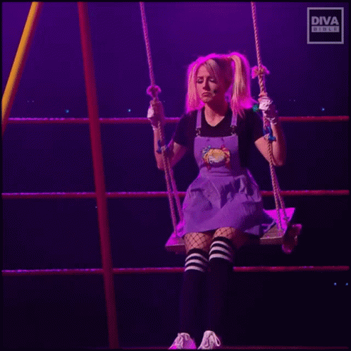 A Woman In A Purple Dress Is Sitting On A Swing In A Ring . GIF