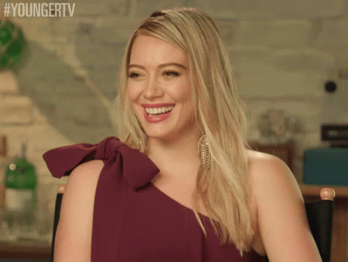 a woman in a purple dress is smiling and sitting in a chair with #youngertv written above her