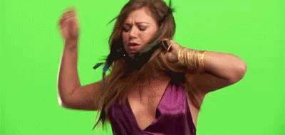 A Woman In A Purple Dress Is Standing In Front Of A Green Screen And Holding Her Hair . GIF