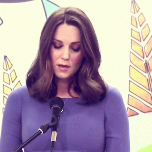A Woman In A Purple Dress Is Standing In Front Of A Microphone GIF